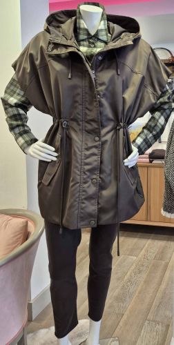 Parka femme kaki à capuche et taille ajustable, portée sur une chemise à carreaux et un pantalon foncé.
